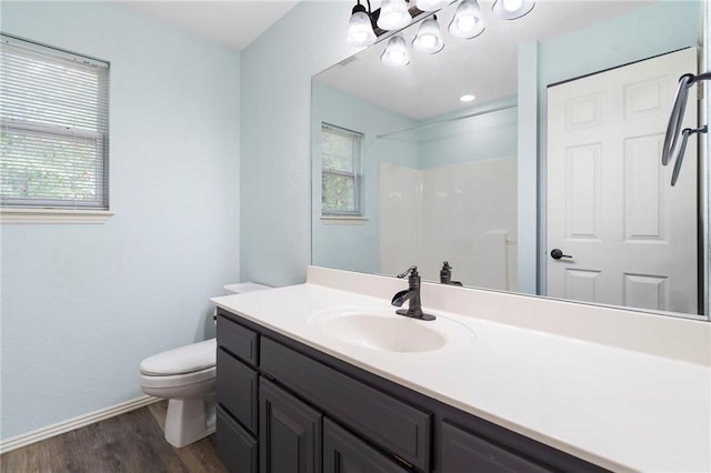 full bath with vanity, wood finished floors, an inviting chandelier, walk in shower, and toilet