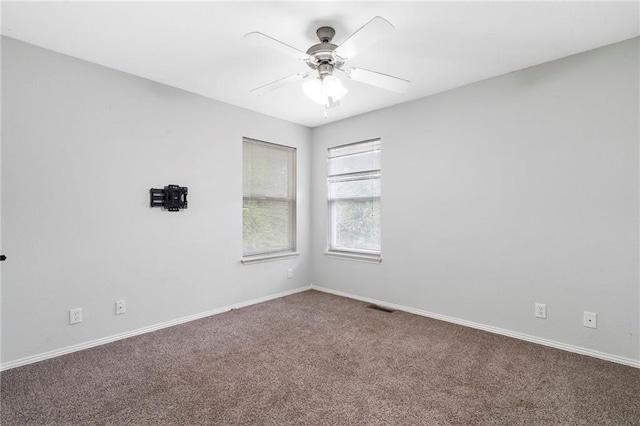 carpeted spare room featuring baseboards, visible vents, and ceiling fan