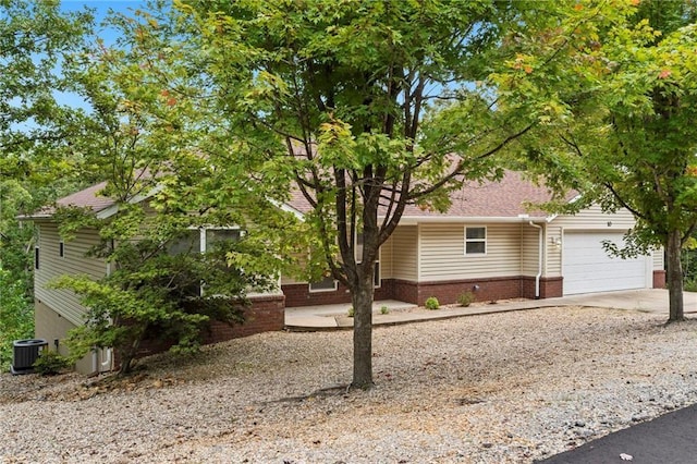 view of home's exterior with cooling unit, brick siding, a garage, and driveway