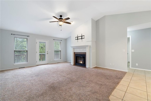 unfurnished living room with ceiling fan, a fireplace with flush hearth, lofted ceiling, light carpet, and light tile patterned flooring