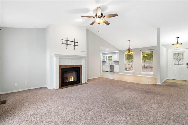 unfurnished living room with light carpet, high vaulted ceiling, a ceiling fan, a tiled fireplace, and baseboards