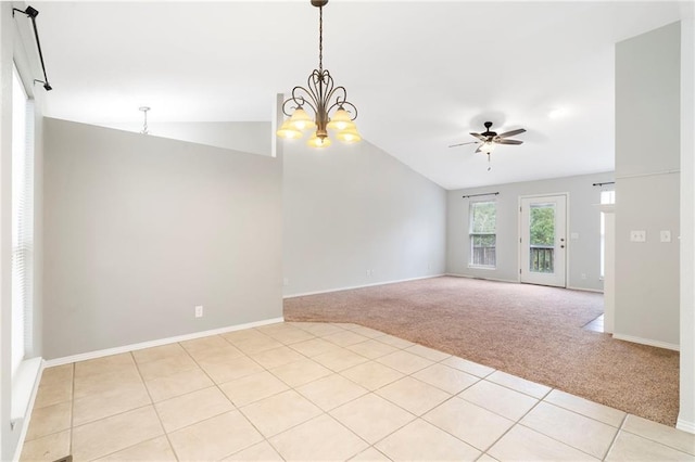 empty room featuring light carpet, lofted ceiling, ceiling fan with notable chandelier, light tile patterned floors, and baseboards