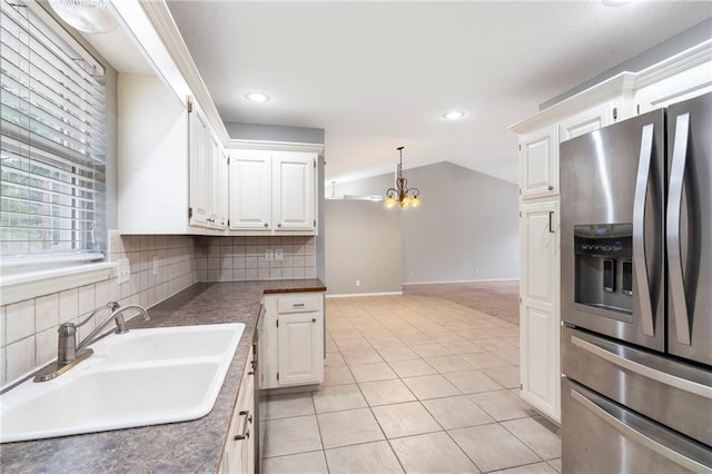 kitchen featuring a chandelier, vaulted ceiling, light tile patterned floors, stainless steel fridge, and a sink