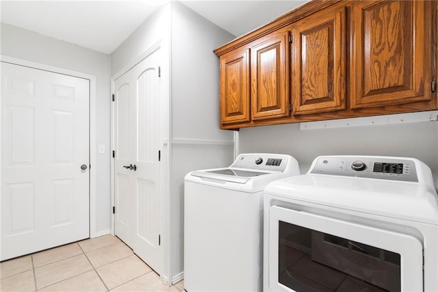 laundry room with washer and dryer, cabinet space, and light tile patterned flooring