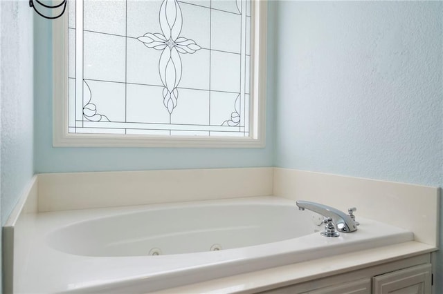 full bathroom featuring a tub with jets and a textured wall