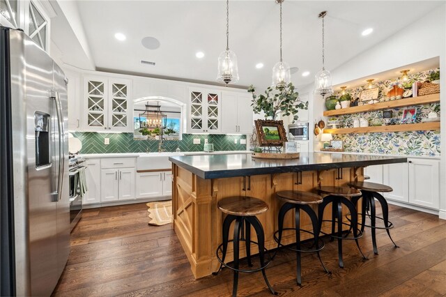 kitchen featuring white cabinets, dark wood-style flooring, appliances with stainless steel finishes, and a center island