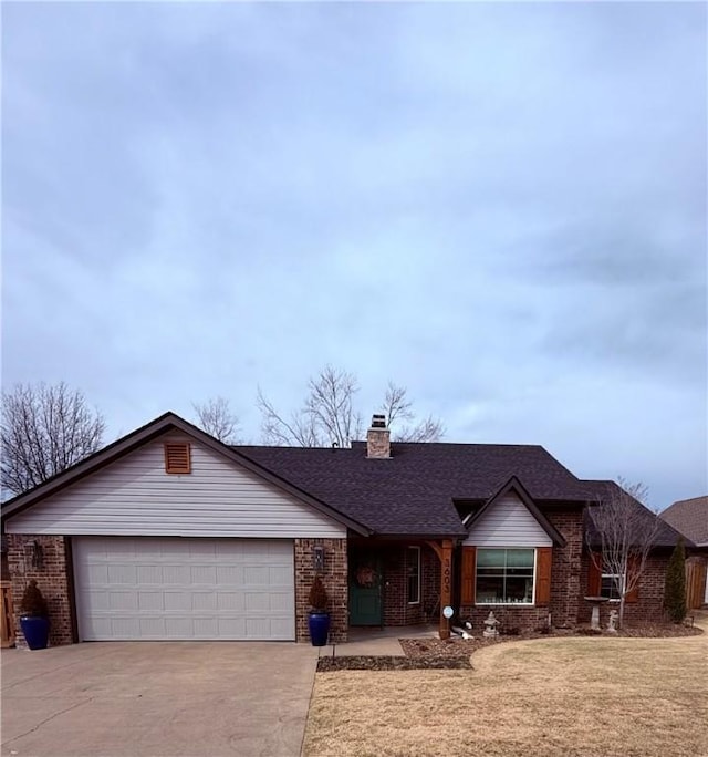 single story home featuring driveway, an attached garage, a chimney, a front lawn, and brick siding