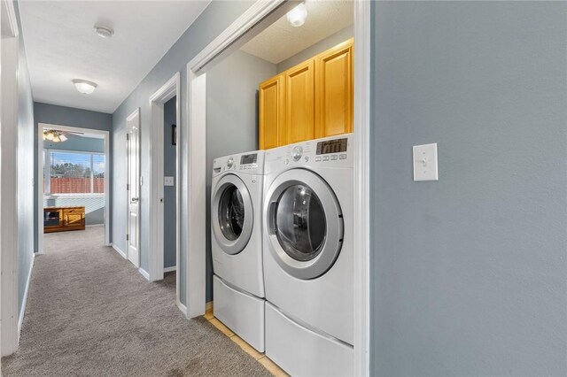 clothes washing area featuring separate washer and dryer, cabinet space, light colored carpet, and baseboards