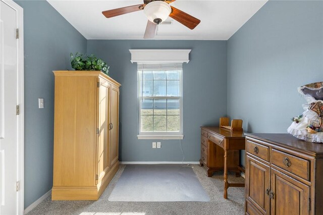 home office featuring light colored carpet, a ceiling fan, and baseboards