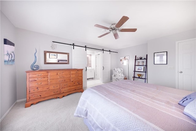 bedroom featuring ceiling fan, baseboards, carpet, a barn door, and ensuite bath