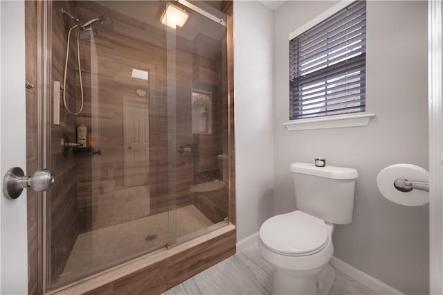 bathroom featuring a shower stall, toilet, and baseboards