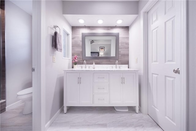 bathroom with double vanity, toilet, marble finish floor, and a sink