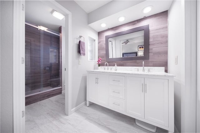 full bathroom featuring a sink, marble finish floor, a shower stall, and double vanity