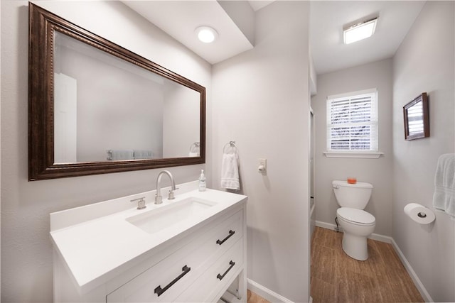 full bath featuring toilet, wood finished floors, shower / washtub combination, baseboards, and vanity