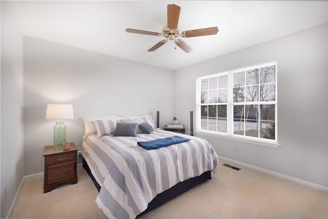 bedroom with a ceiling fan, baseboards, visible vents, and light carpet