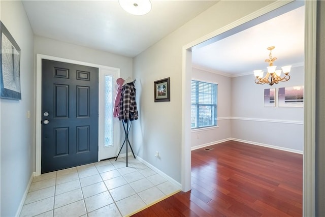 entryway with baseboards, an inviting chandelier, wood finished floors, and crown molding