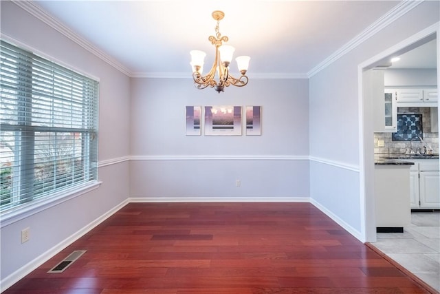 unfurnished dining area with visible vents, a sink, wood finished floors, an inviting chandelier, and baseboards