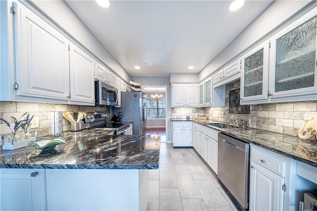 kitchen with dark stone countertops, white cabinets, stainless steel appliances, and a sink