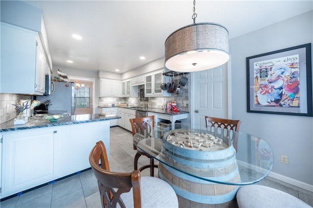 dining space with light tile patterned flooring, a notable chandelier, recessed lighting, and baseboards