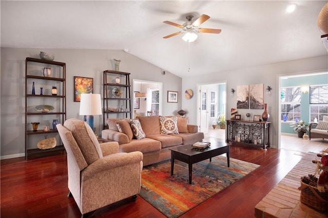 living area with baseboards, dark wood-type flooring, ceiling fan, and vaulted ceiling