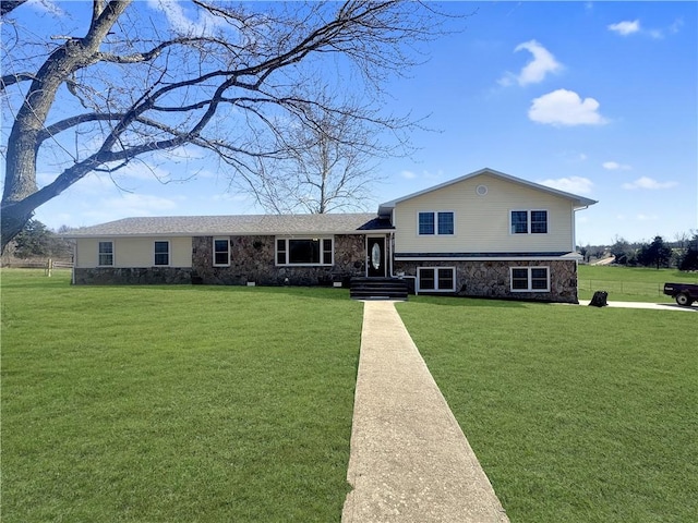 tri-level home featuring a front yard and stone siding