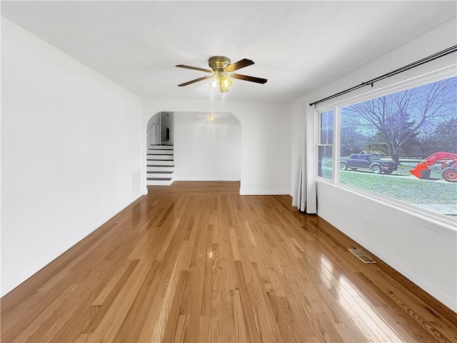 spare room with arched walkways, visible vents, baseboards, and light wood-style floors