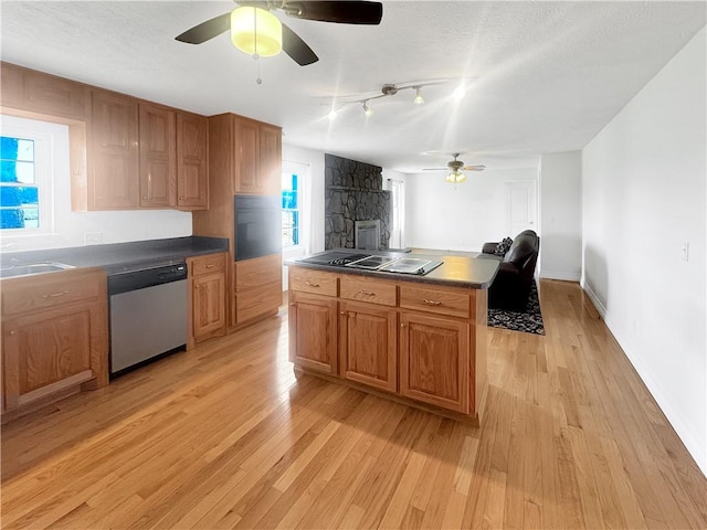 kitchen with light wood-type flooring, dark countertops, dishwasher, and stovetop with downdraft