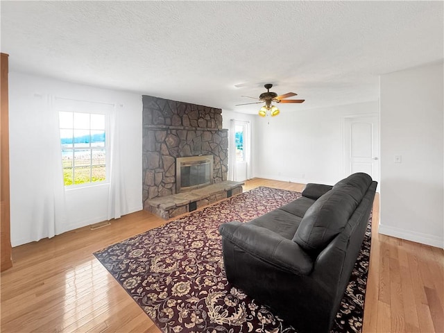 living room featuring a fireplace, visible vents, wood-type flooring, and a textured ceiling