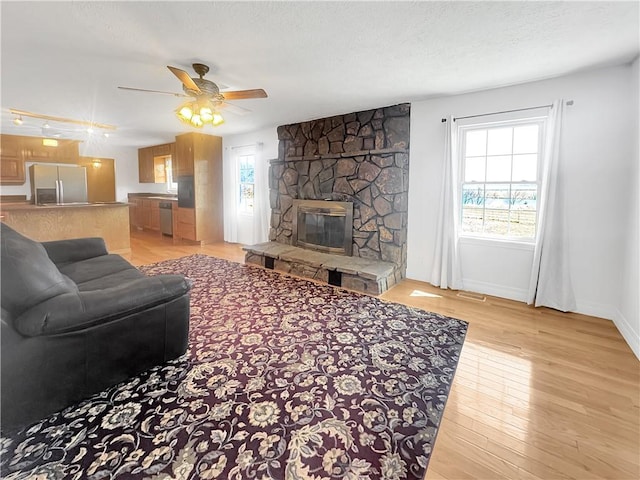 living room with baseboards, light wood-style floors, a fireplace, and a textured ceiling