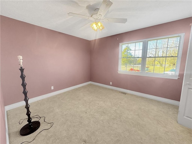 unfurnished room with light carpet, visible vents, ceiling fan, and baseboards