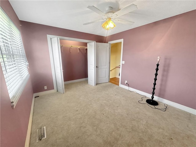 unfurnished bedroom featuring a ceiling fan, visible vents, baseboards, carpet floors, and a closet