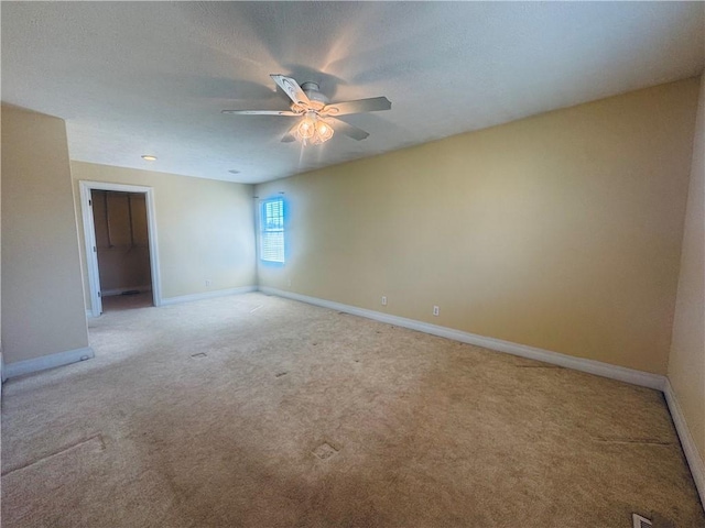 empty room with baseboards, light colored carpet, a ceiling fan, and a textured ceiling