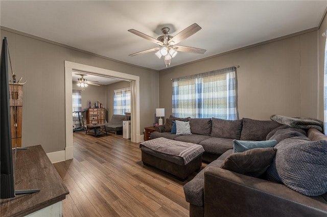 living area featuring baseboards, a ceiling fan, and wood finished floors