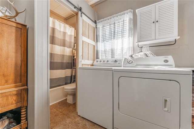 washroom featuring laundry area, light tile patterned floors, separate washer and dryer, and a barn door