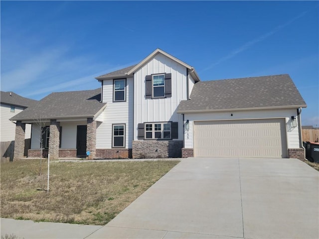 view of front of property featuring a front yard, driveway, an attached garage, board and batten siding, and brick siding