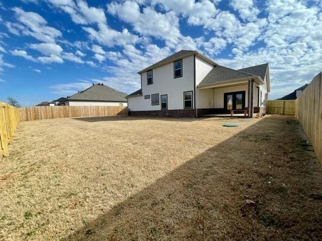 back of house featuring a lawn, a fenced backyard, and french doors