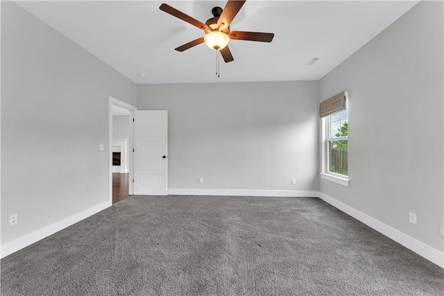carpeted spare room with baseboards, a ceiling fan, and visible vents