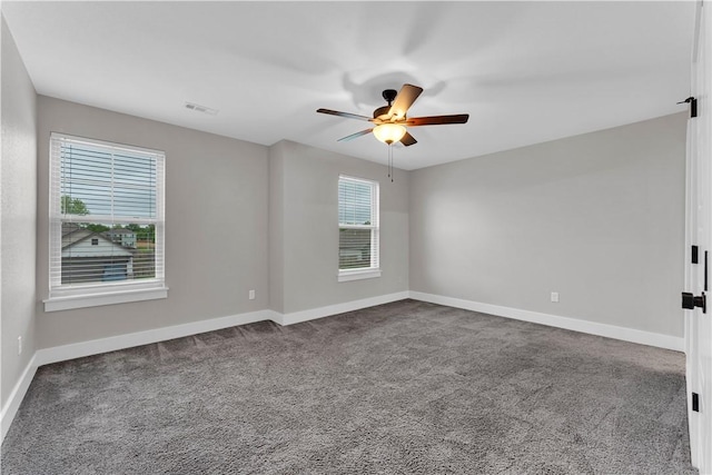spare room with baseboards, ceiling fan, visible vents, and dark carpet