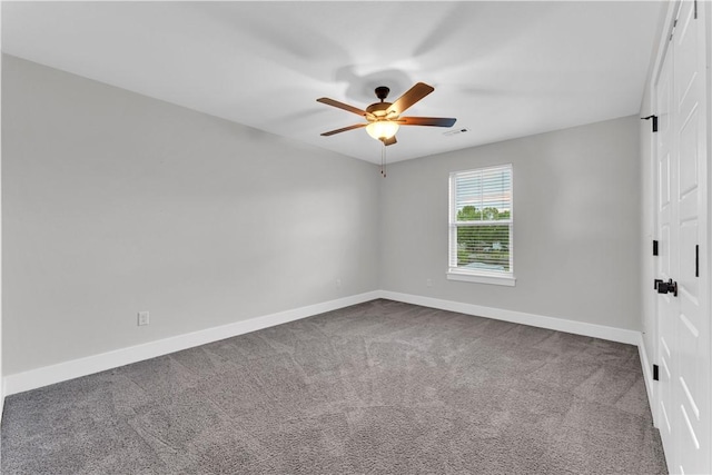 empty room with baseboards, ceiling fan, visible vents, and dark carpet