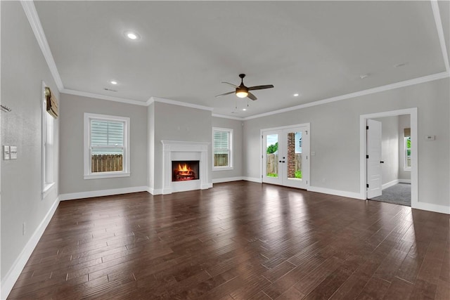 unfurnished living room featuring a ceiling fan, crown molding, baseboards, dark wood-style floors, and a warm lit fireplace