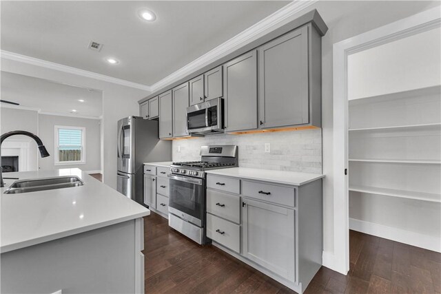 kitchen featuring crown molding, appliances with stainless steel finishes, a sink, dark wood finished floors, and gray cabinets