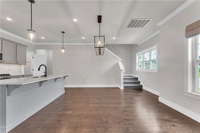 kitchen featuring a kitchen breakfast bar, visible vents, a sink, light countertops, and ornamental molding