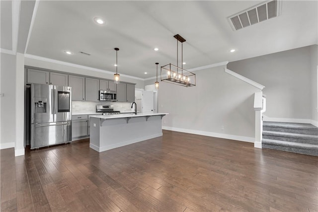 kitchen with visible vents, appliances with stainless steel finishes, gray cabinetry, light countertops, and a breakfast bar