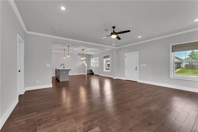 unfurnished living room featuring baseboards, a ceiling fan, stairs, and a wealth of natural light