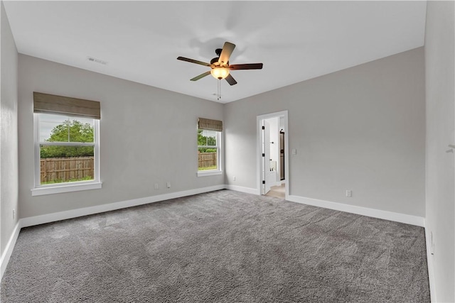 empty room with baseboards, a ceiling fan, carpet, and visible vents