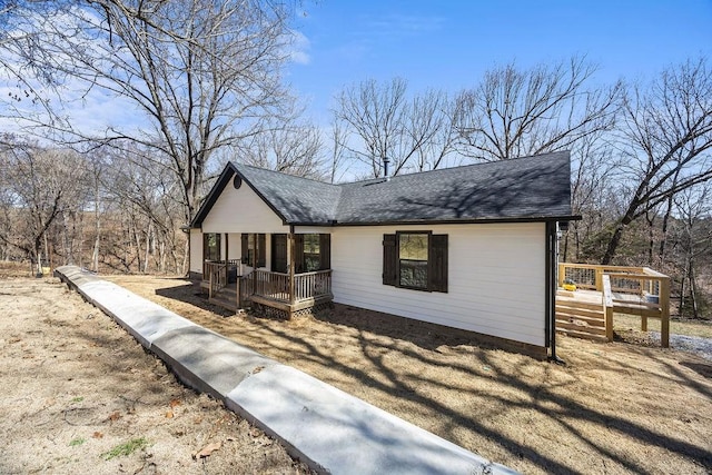 view of front of home featuring a wooden deck, covered porch, and a shingled roof