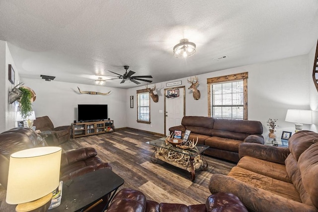 living room with a ceiling fan, wood finished floors, visible vents, and a textured ceiling