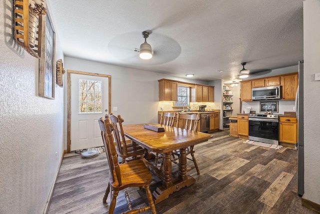 dining area with a textured ceiling, ceiling fan, dark wood-style flooring, and a textured wall