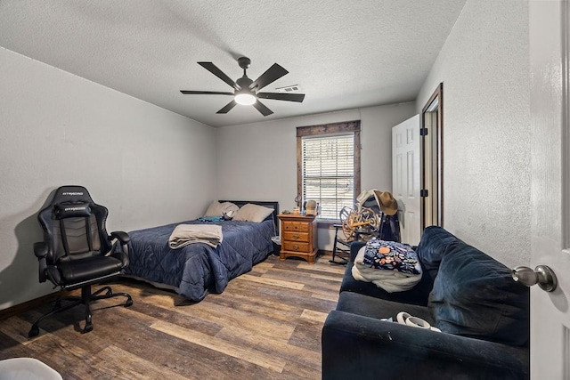 bedroom with visible vents, wood finished floors, a textured wall, a textured ceiling, and a ceiling fan