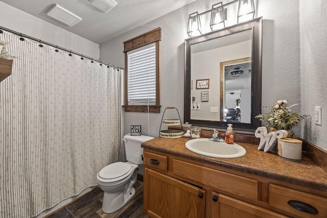 full bath with visible vents, toilet, wood finished floors, vanity, and a textured wall